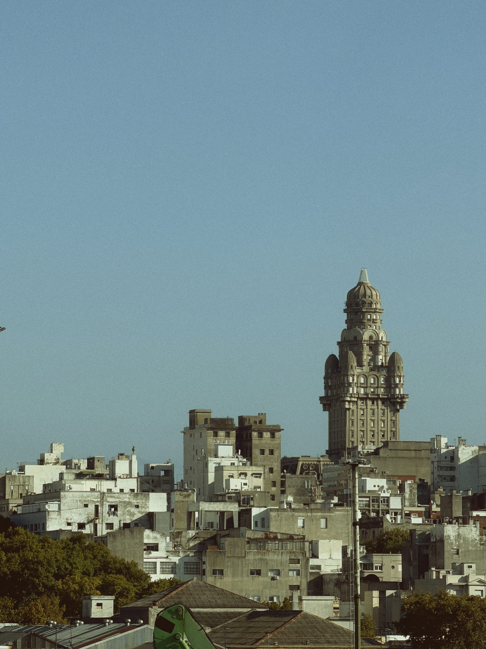 Palacio Salvo, with its domed tower, rises above the rooftops and white buildings of Montevideo against a blue sky.
